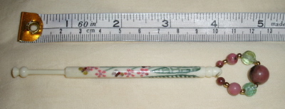 bone bobbin with inlaid mother of pearl and paint decoration